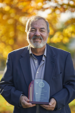 Man holding plaque outside on a fall day