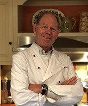Chris Nesson '78 posing with arms crossed wearing a chef's coat