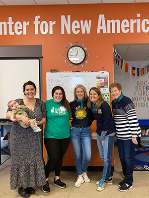 5 women and a baby smiling for a photo at the Center for New Americans clothing drive project