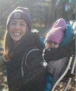 Woman smiling with child in a backpack carrier