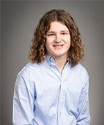 Picture of SNHU student with curly hair and a blue button down, smiling