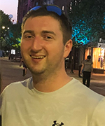 Man in white shirt standing outside and smiling