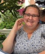 Picture of person wearing glasses with flower behind their ear smiling