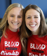 Two women smiling wearing blood donation shirts