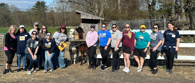 Group posed in front of farm animal pen outdoors