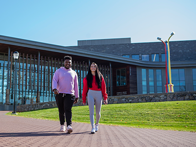 Two students walk outside of a library