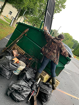 Person throwing bags of trash in dumpster