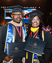 Couple together at graduation holding their degrees