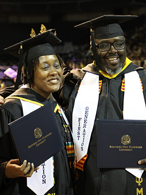 First-generation students in their caps & gowns holding their dipolmas