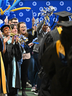 Graduates walking through the celebratory clap-line at commencement.