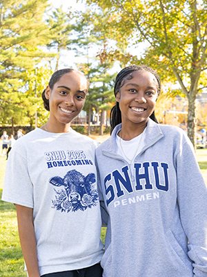Two people wearing SNHU shirts and smiling at Homecoming street fair celebration.