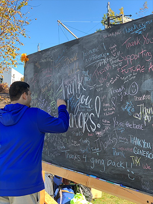 Man writes on chalkboard filled with words of thanks